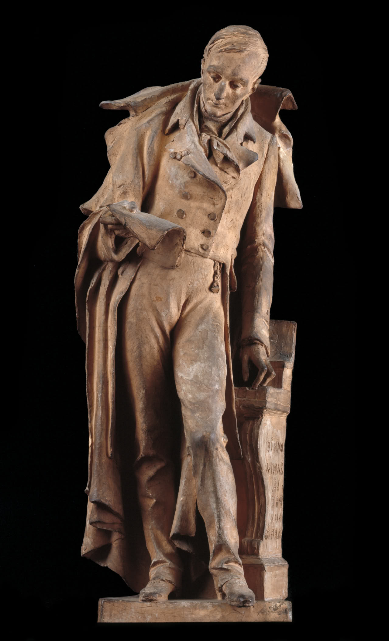 Statue d'un homme en pied, vêtu d'un manteau et d'une tenue formelle, tenant un document dans sa main droite et s'appuyant sur un meuble.
